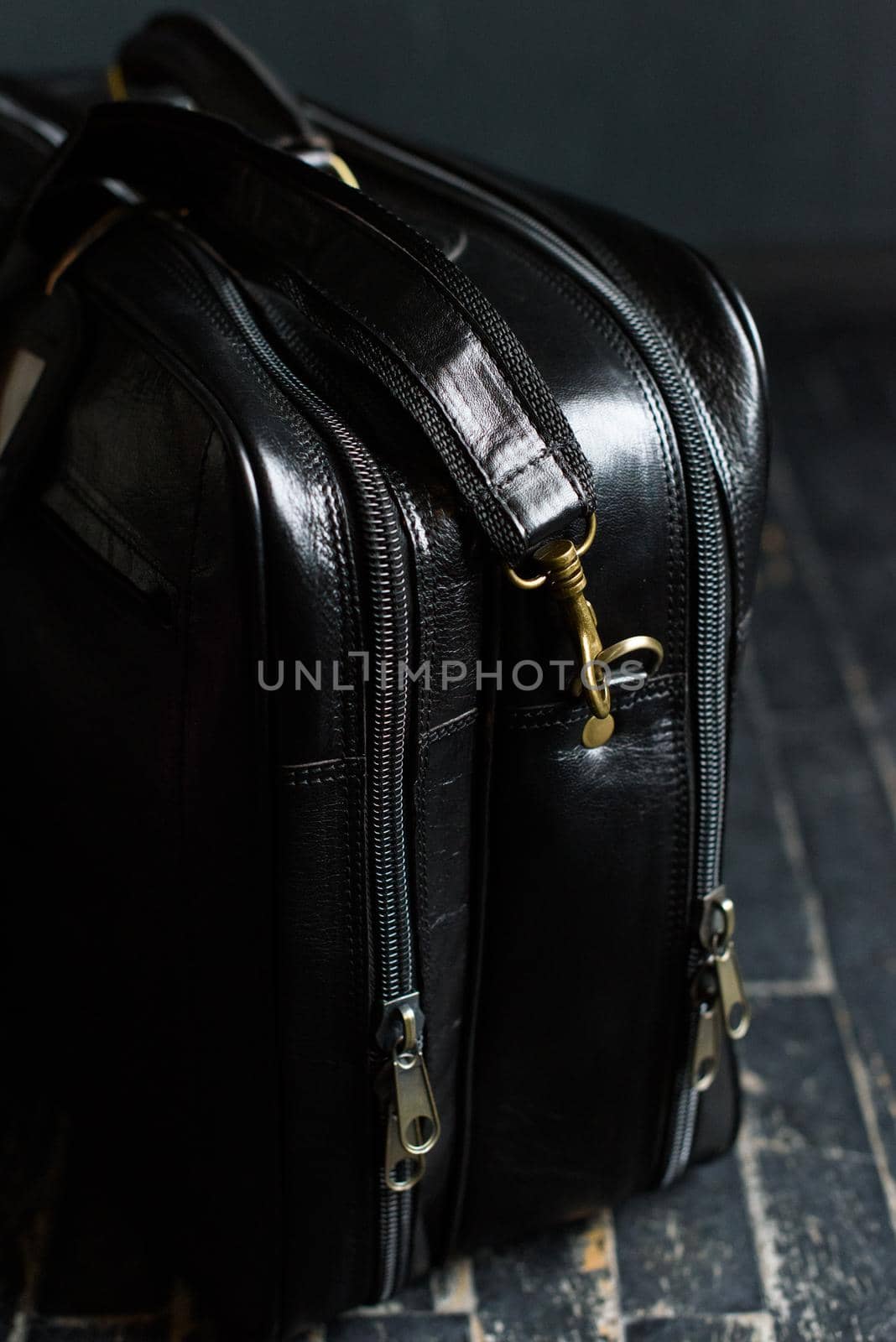 Leather black travel bag, on a black wooden floor. soft light