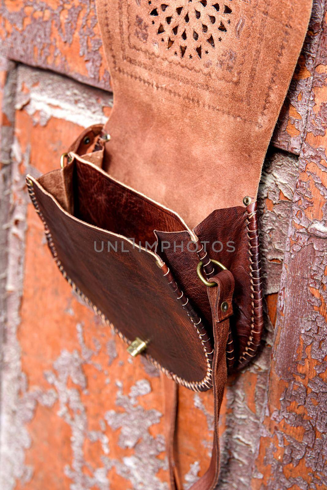 small brown women's leather bag with a carved pattern. Outdoors photo, side view