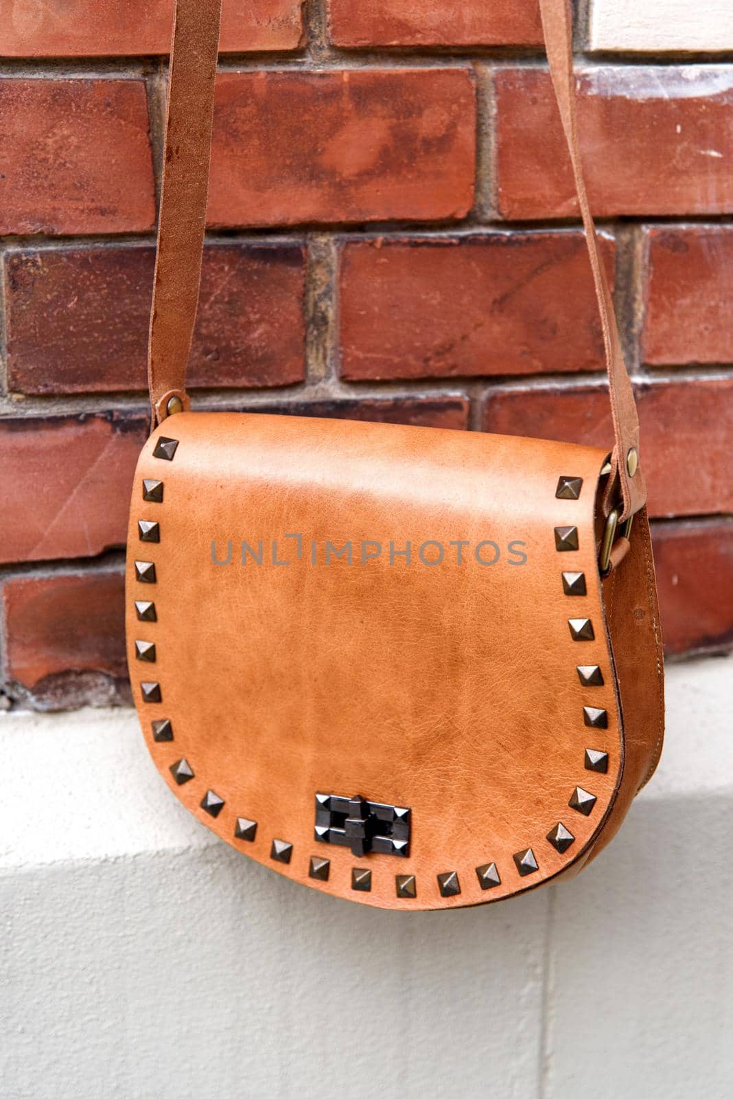 small yellow women's leather bag with rivets. selective focus. outdoors photo