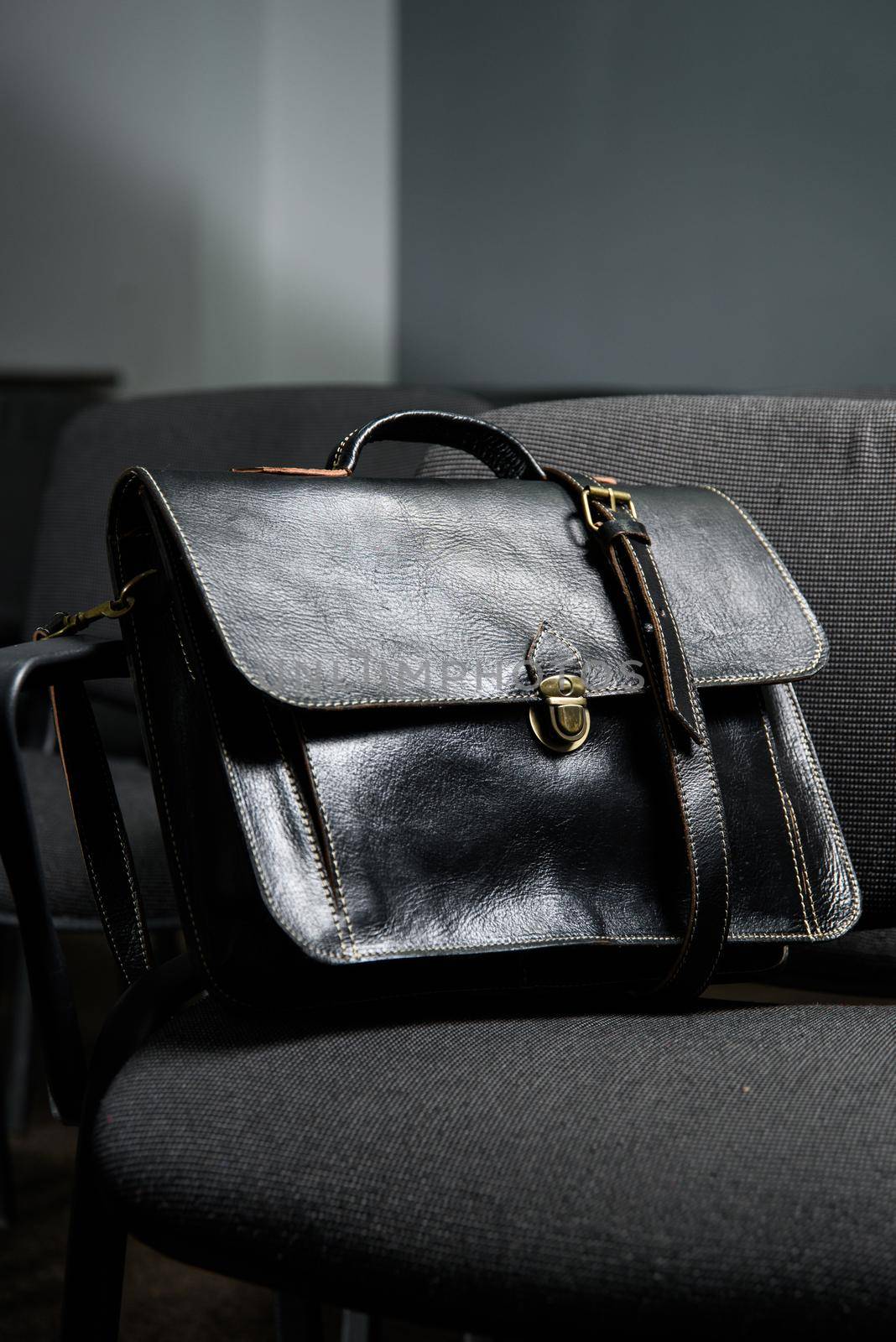 Black leather briefcase with antique and retro look for man on a office chair. photo taken in a conference hall by Ashtray25