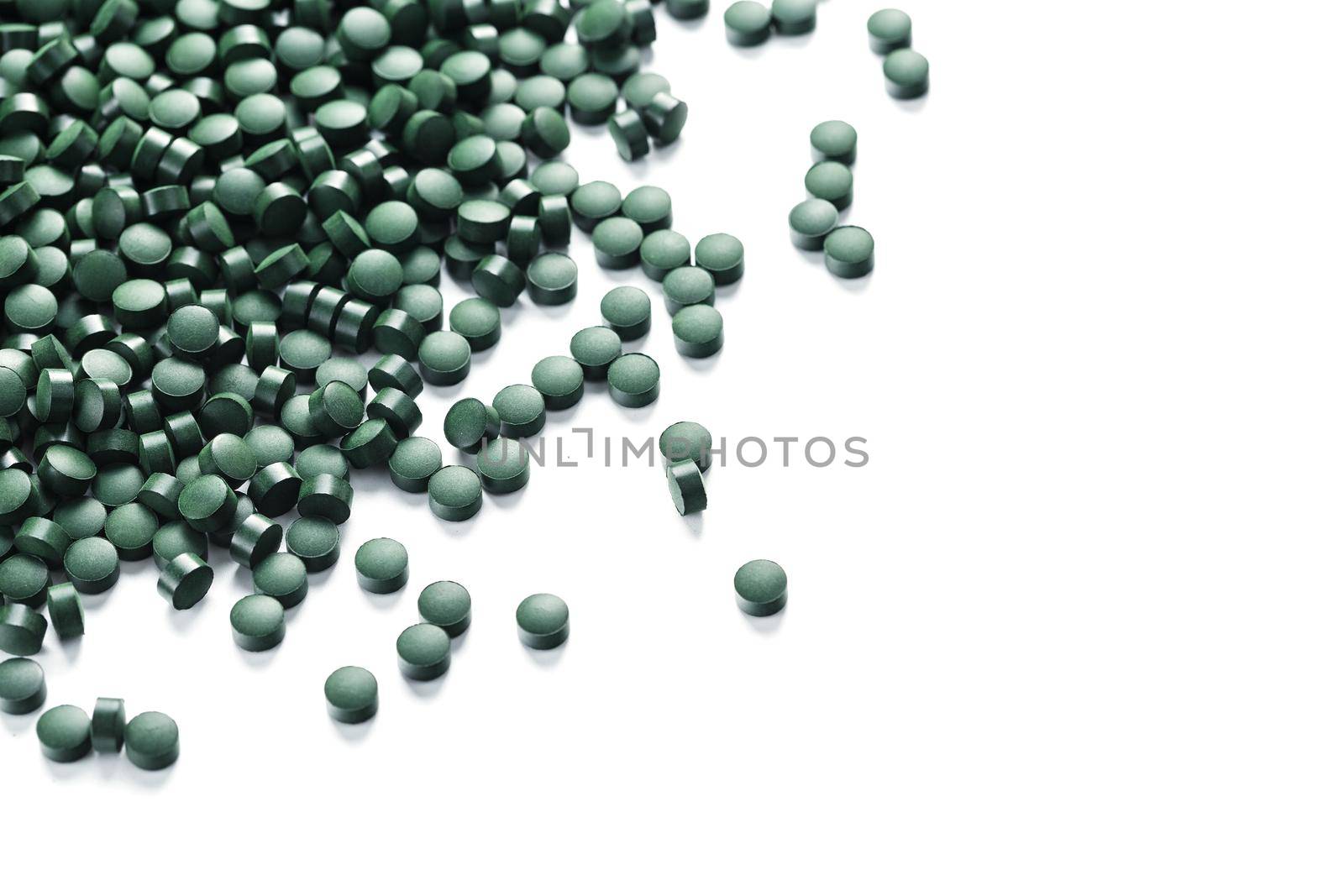 Green tablets made of natural organic spirulina on a white background with free space