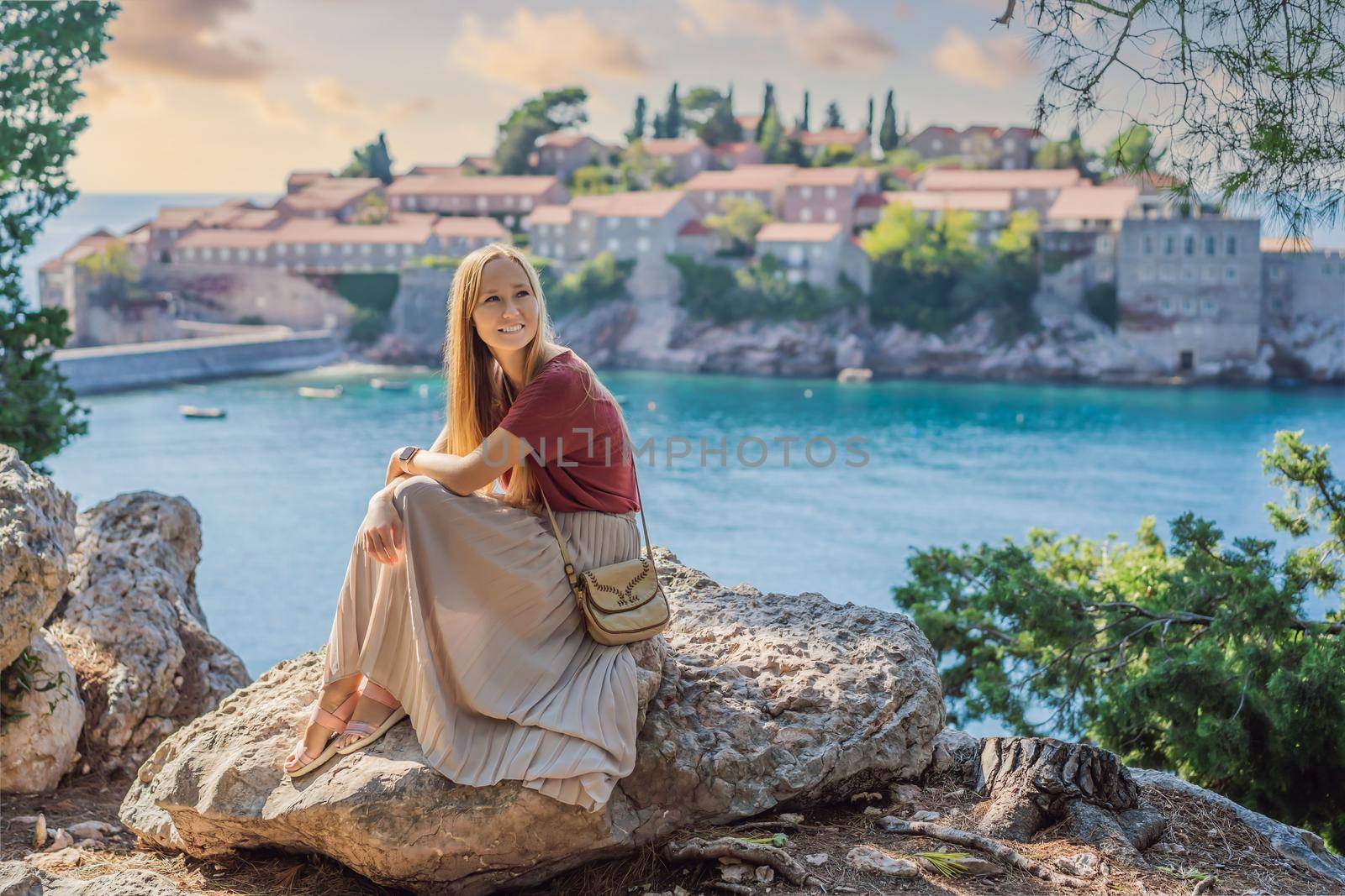 Woman tourist on background of beautiful view of the island of St. Stephen, Sveti Stefan on the Budva Riviera, Budva, Montenegro. Travel to Montenegro concept.