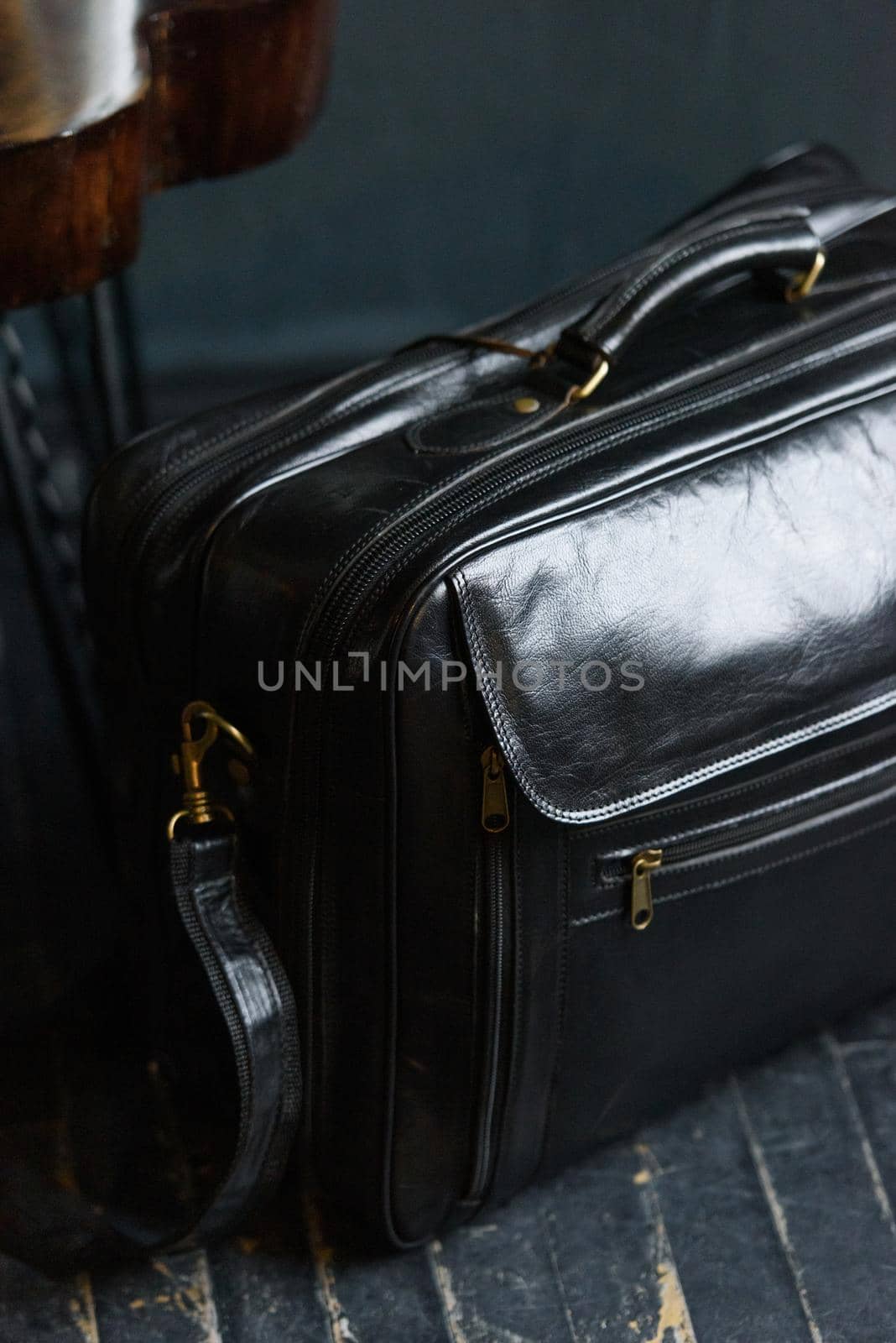 Leather black travel bag, on a black wooden floor. soft light