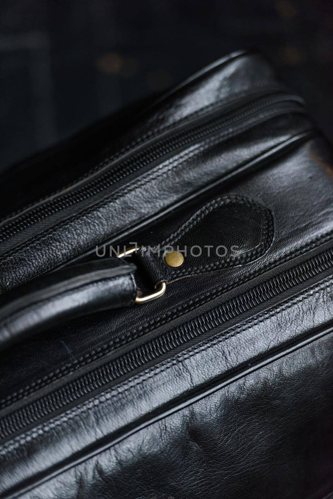 Leather black travel bag, on a black wooden floor. soft light