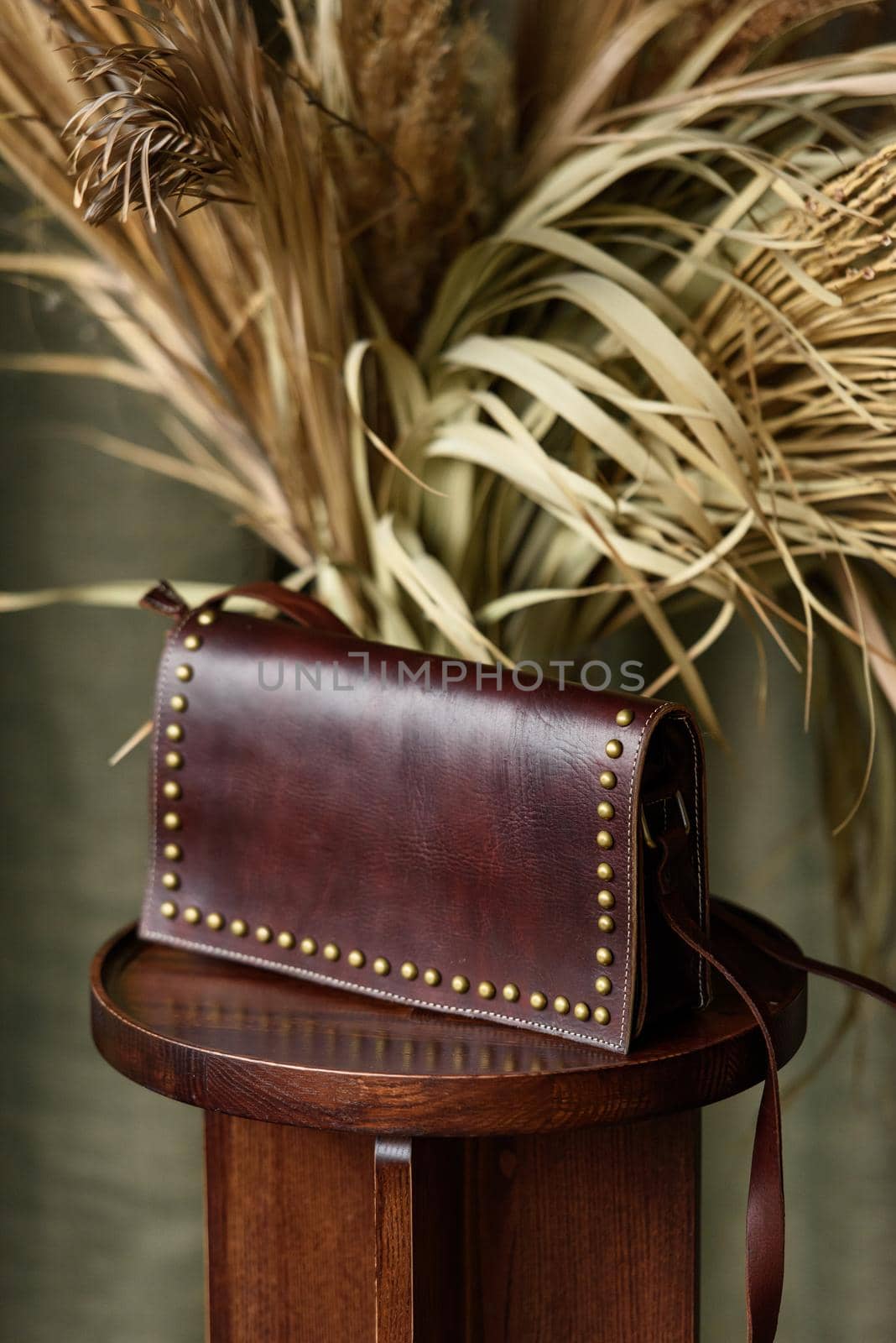 small brown women's leather bag with rivets selective focus. indoor photo