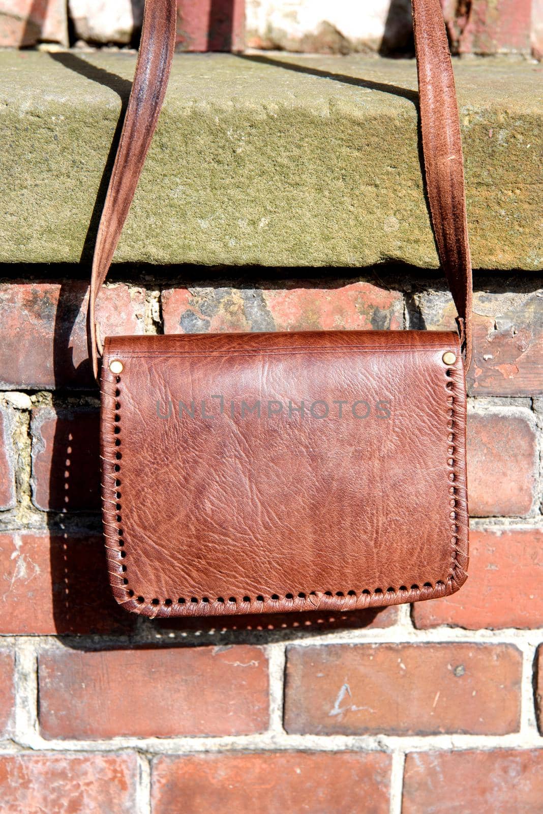 close-up photo of orange leather messanger bag. outdoors photo.