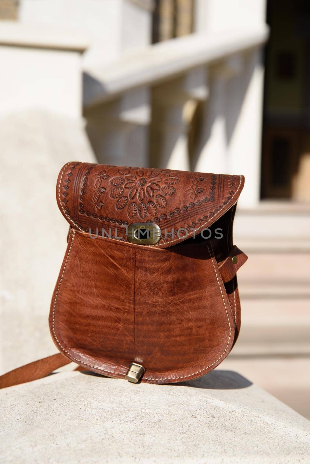 small brown women's leather bag with a carved pattern. street photo