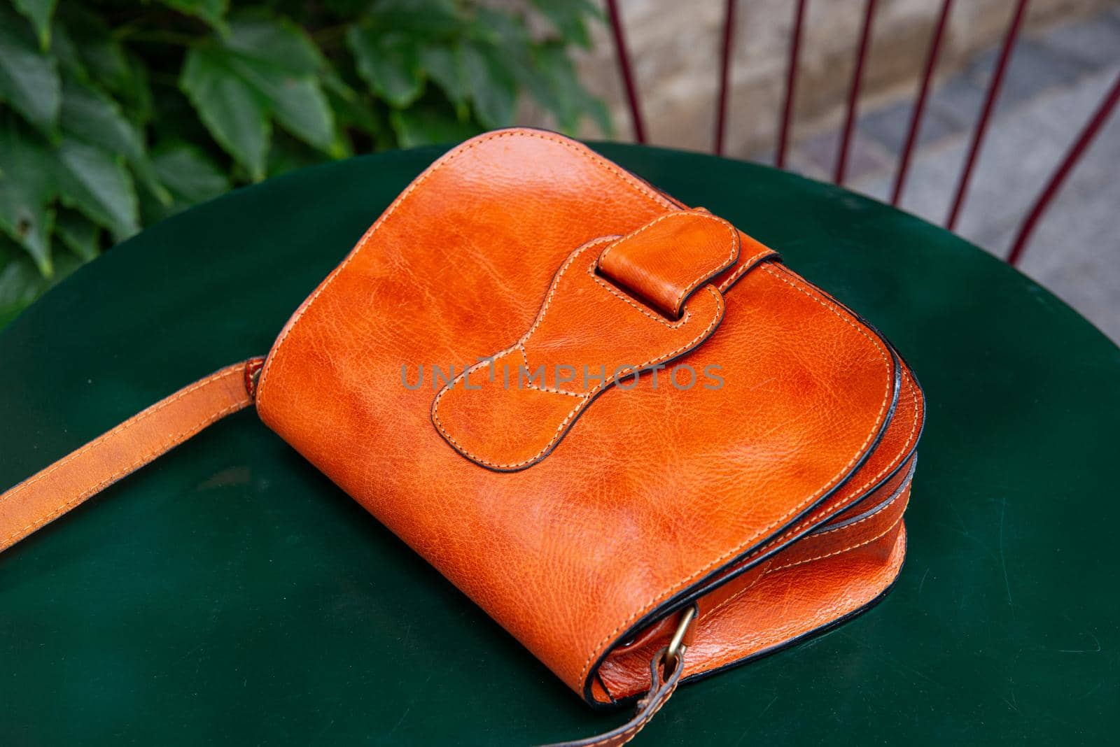 small orange women's leather bag on a green table by Ashtray25