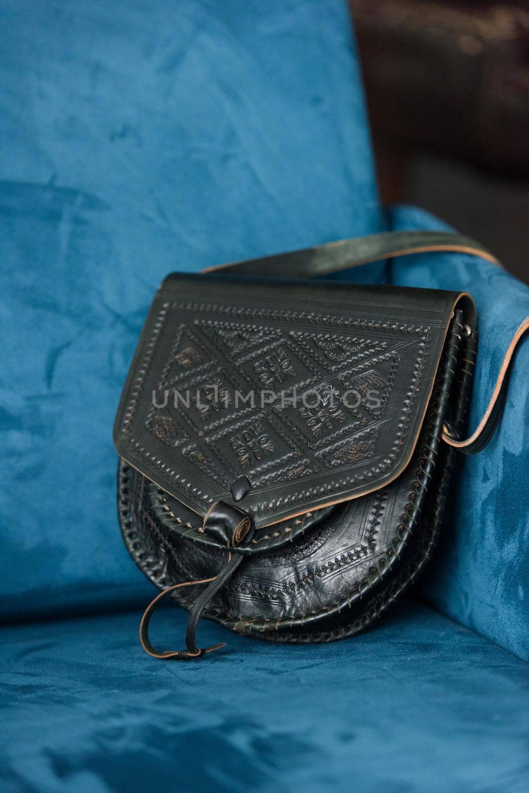 small brown women's leather bag with a carved pattern. indoor photo