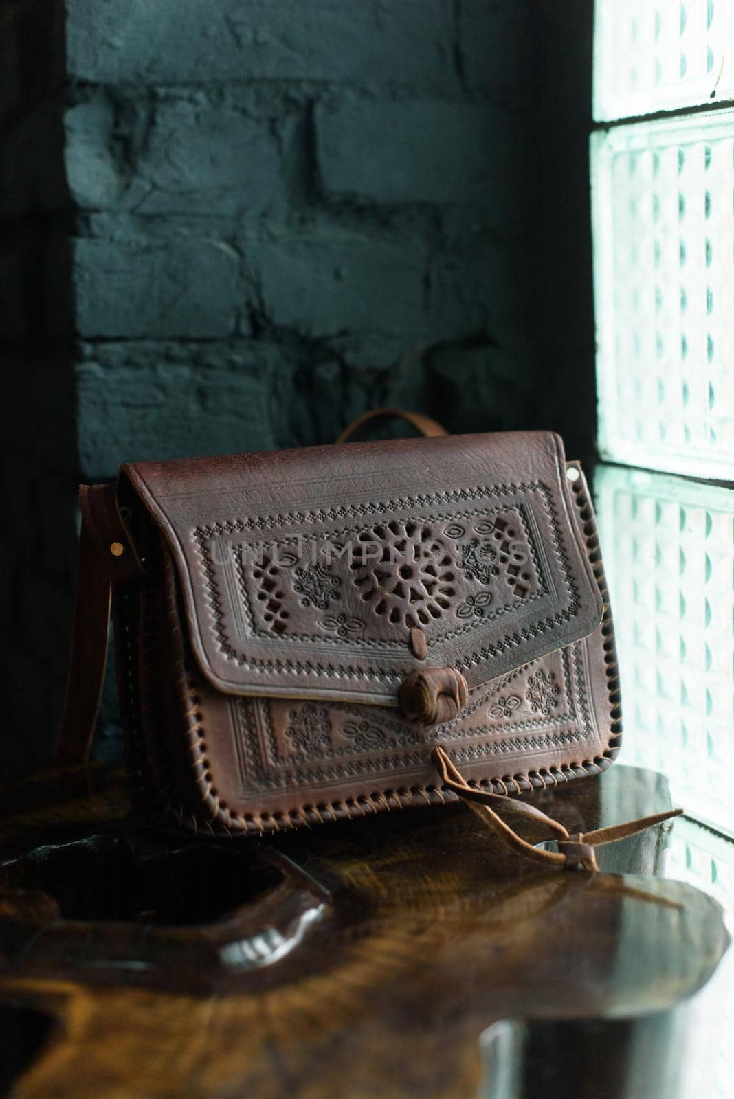small brown women's leather bag with a carved pattern. indoor photo