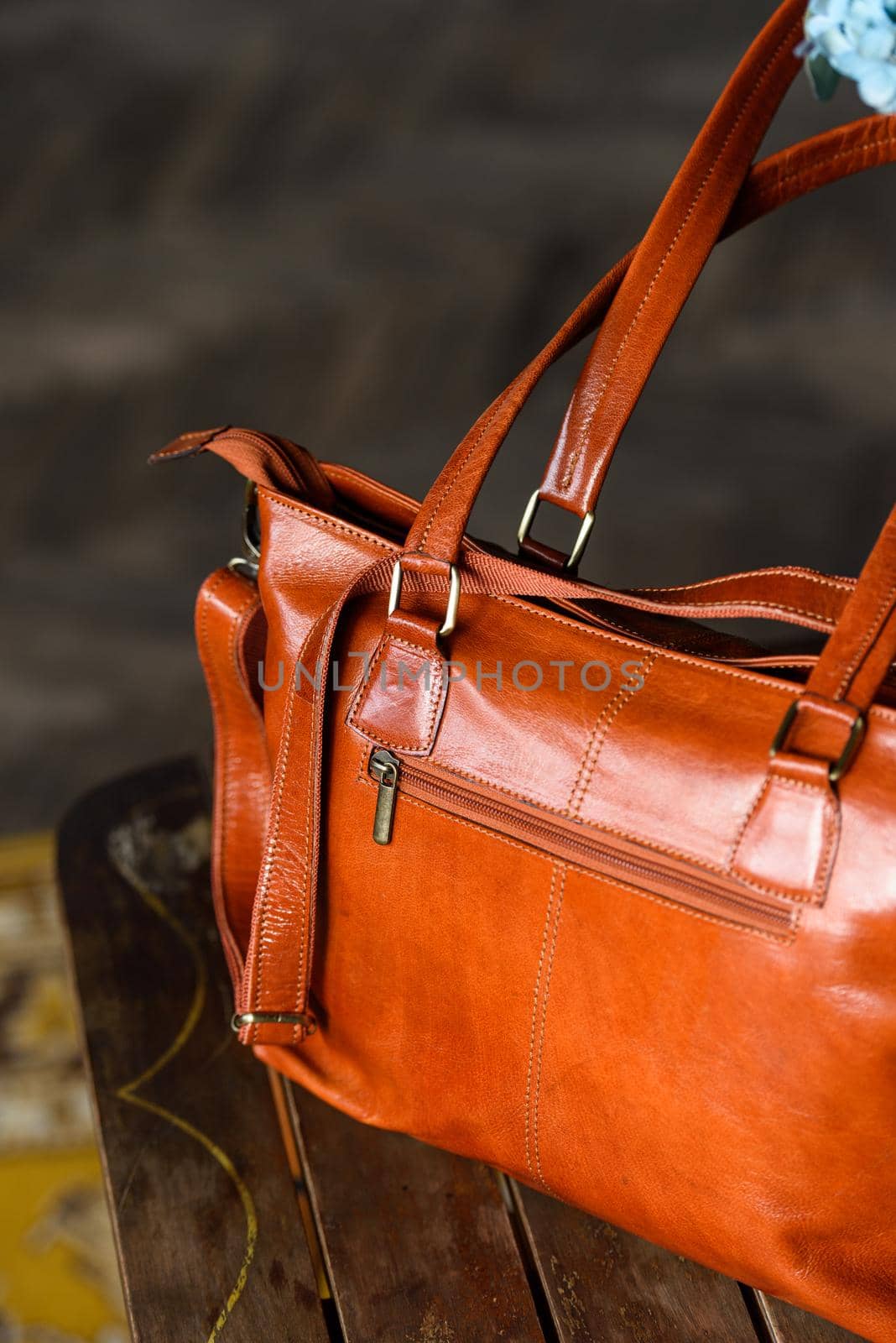 close-up photo of orange leather bag on a wooden table. indoor photo