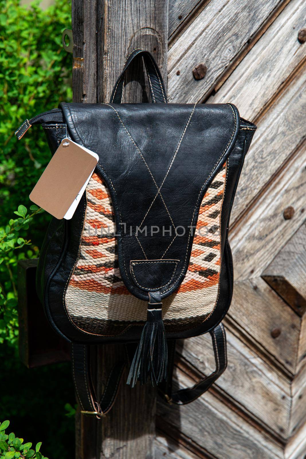 Black leather backpack with a pattern on the wooden door by Ashtray25