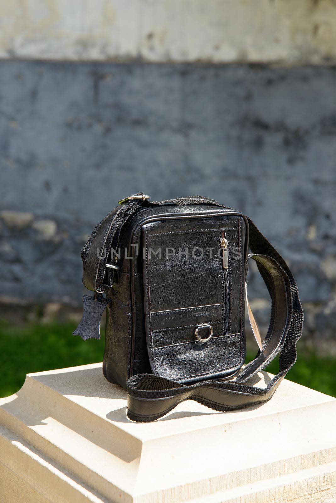 Outdoor photo of a dark brown leather Messenger bag. Close up.