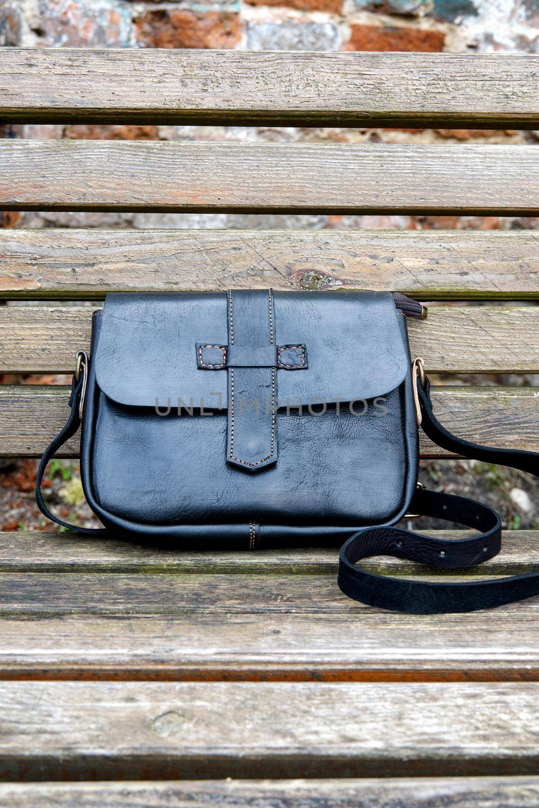 close-up photo of black leather handbag on a wooden bench by Ashtray25