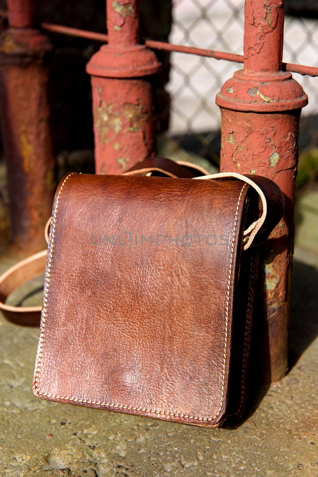 close-up photo of orange leather messanger bag. outdoors photo.