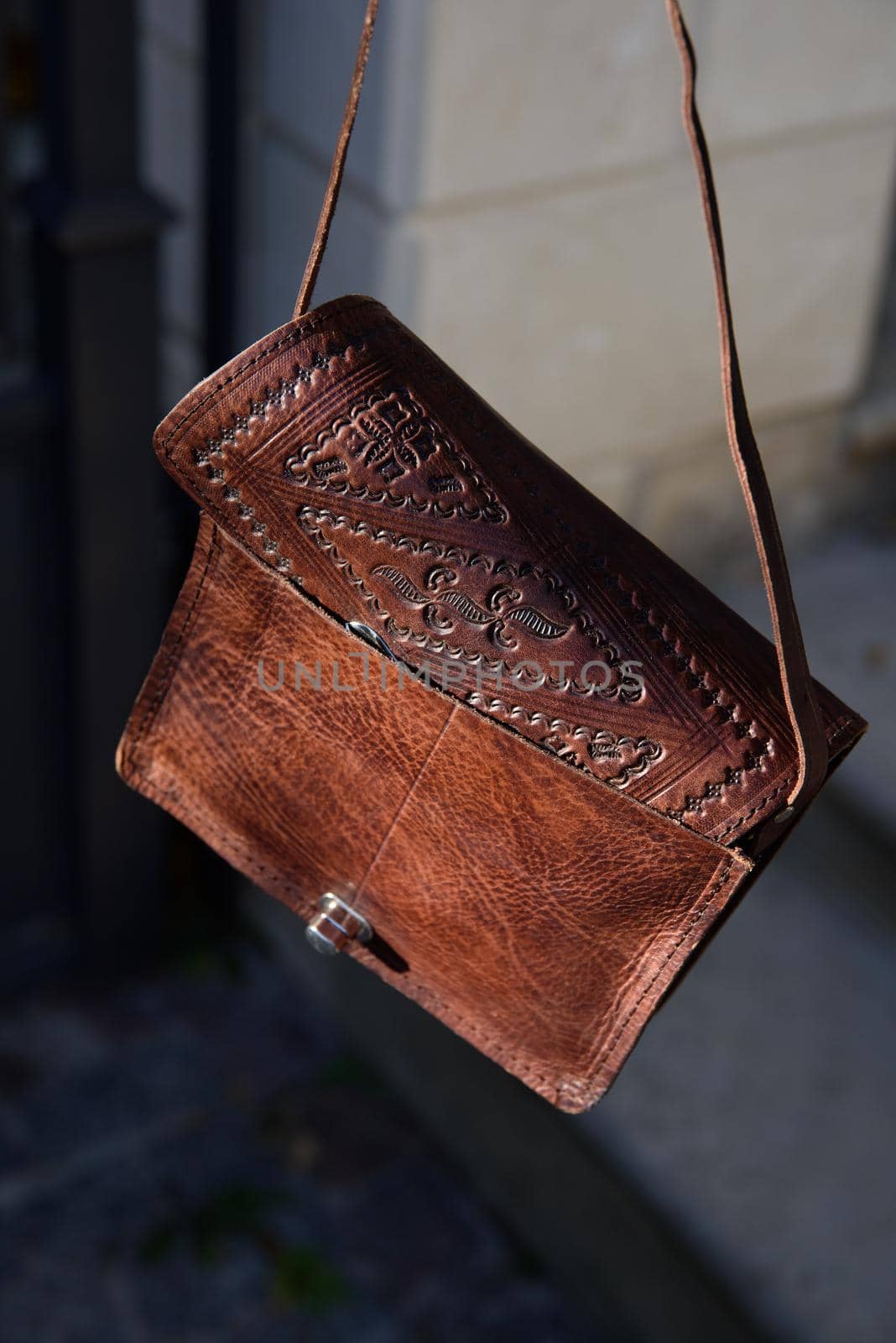 small brown women's leather bag with a carved pattern. street photo