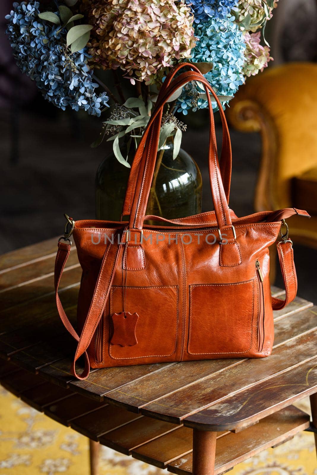 close-up photo of orange leather bag on a wooden table. indoor photo