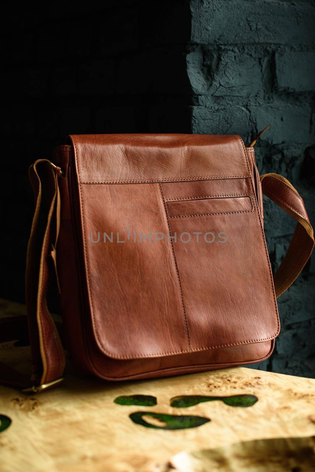 close-up photo of orange leather messanger bag on a wooden table. indoor photo