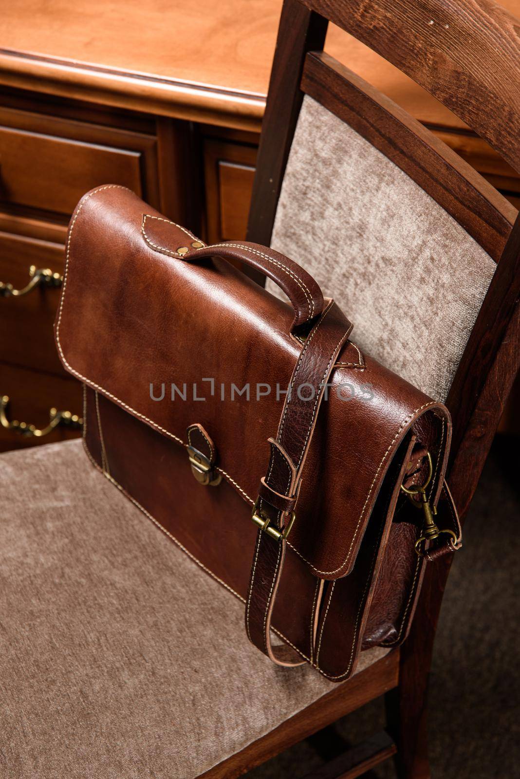 brown leather briefcase with antique and retro look for man on a chair. Hotel room photo by Ashtray25