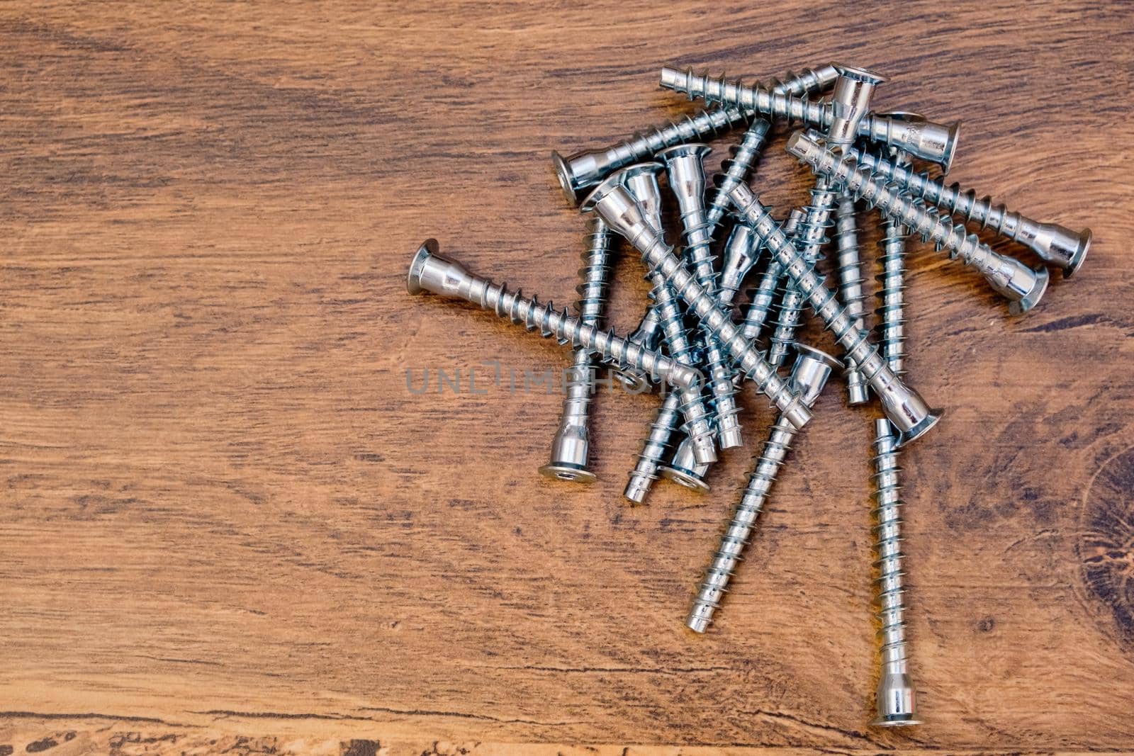 Close up of hex bolts screw for furniture assembly on wooden background. Top view.