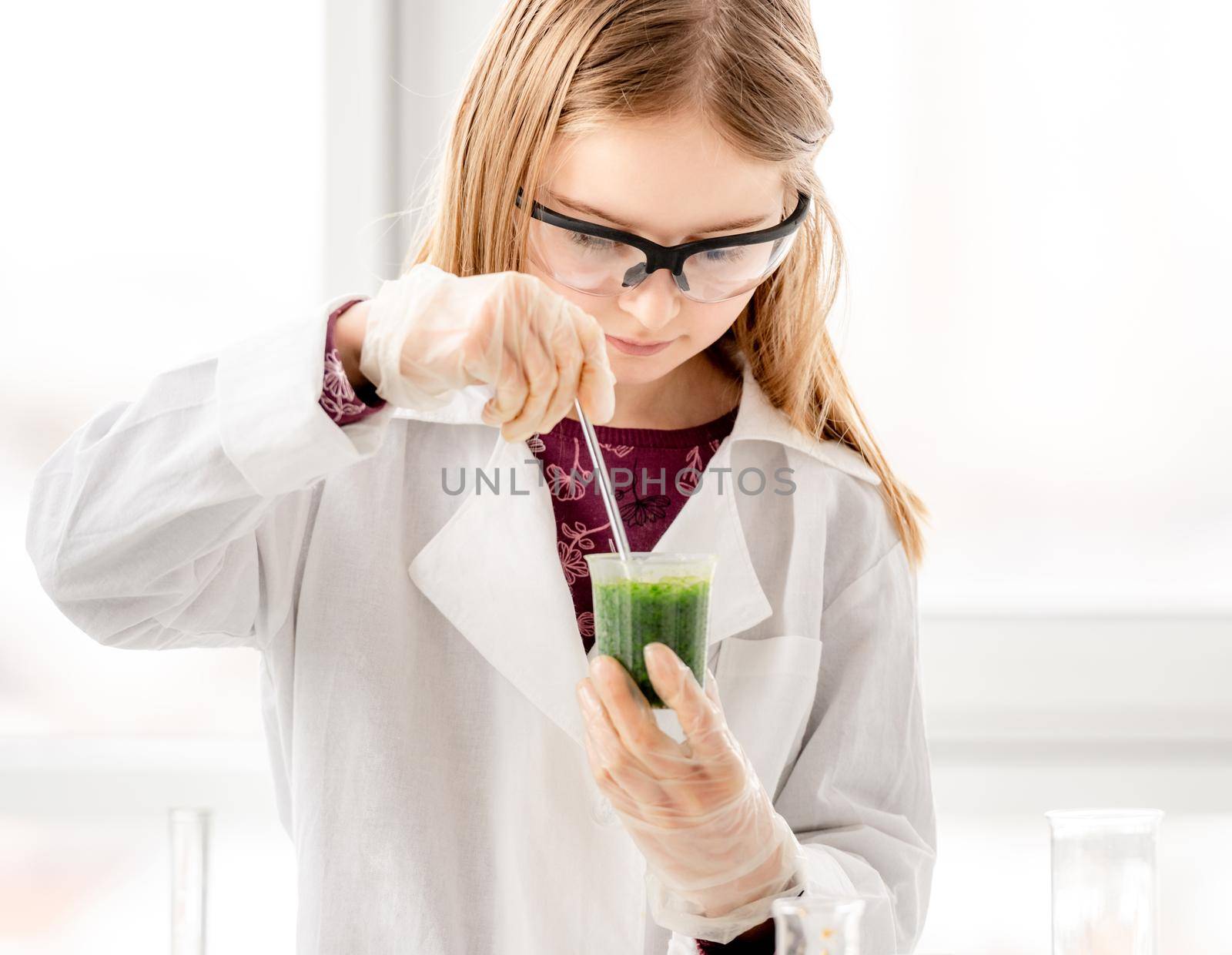 Girl doing scientific chemistry experiment wearing protection glasses. Schoolgirl with equipment and chemical liquids on school lesson