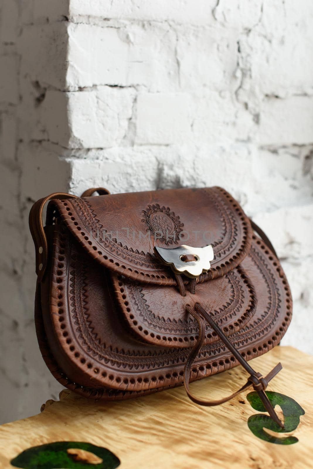 small brown women's leather bag with a carved pattern. indoor photo