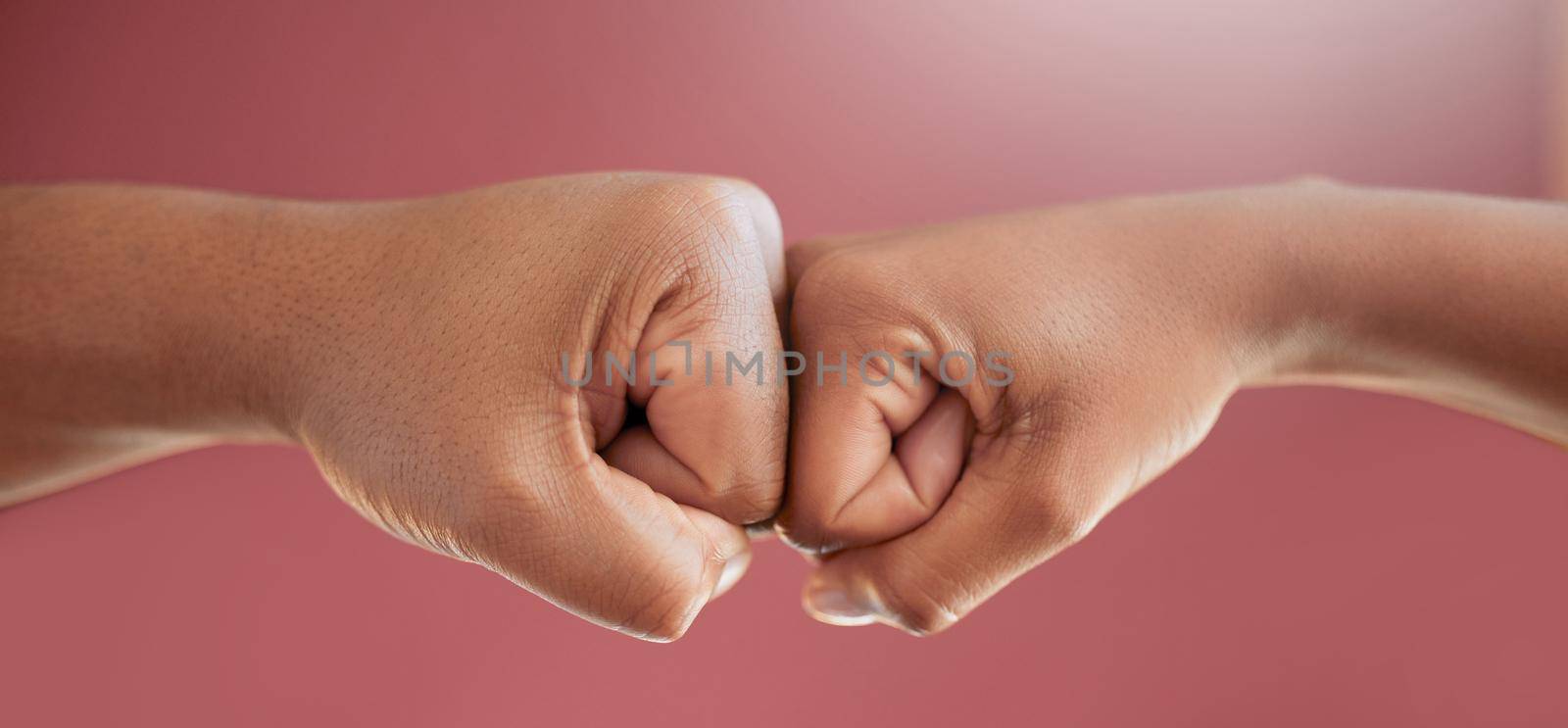 Just like that. Cropped shot of two unrecognizable people fist bumping in studio against a red background. by YuriArcurs