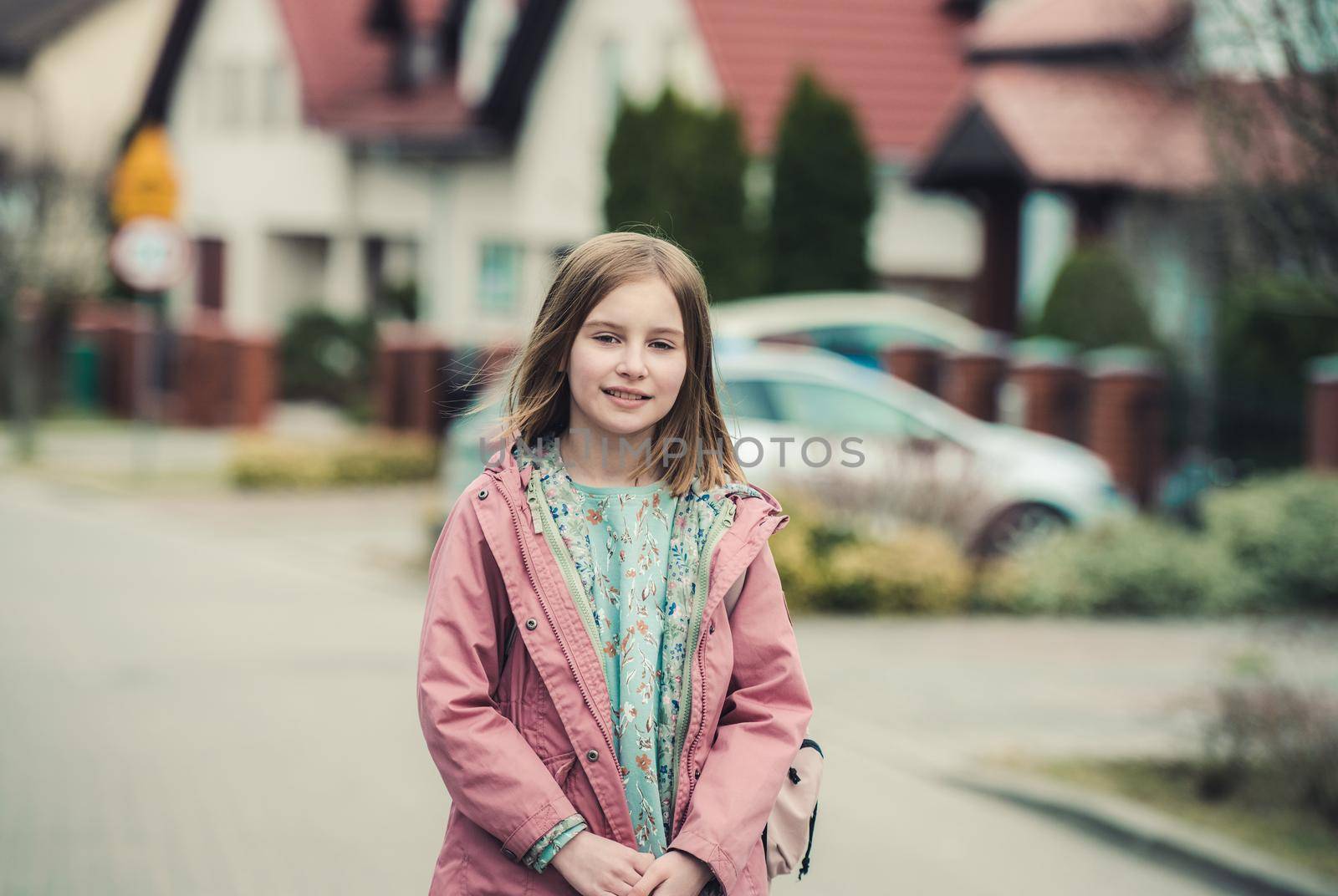 School girl with backpack walks at street. Preteen child kid posing outdoors after college class
