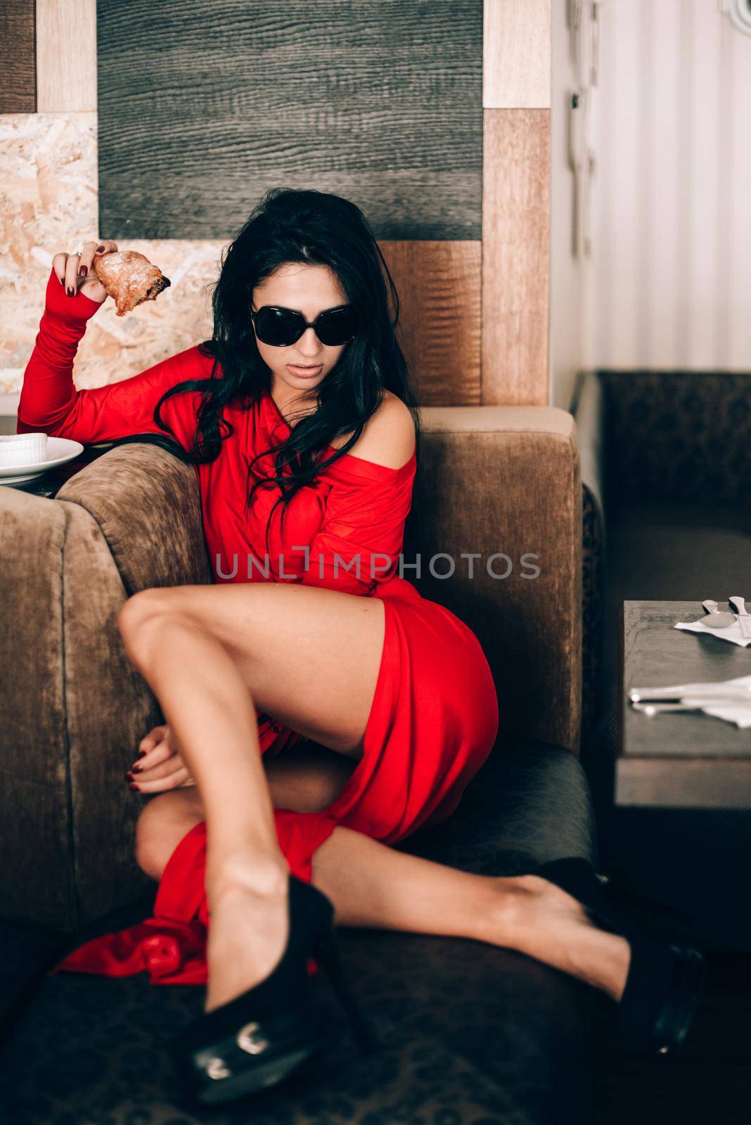 sexy woman in a red dress with black hair eats a croissant. temptation with food. attractive legs. obsession with red. Selective focus, film grain by Ashtray25