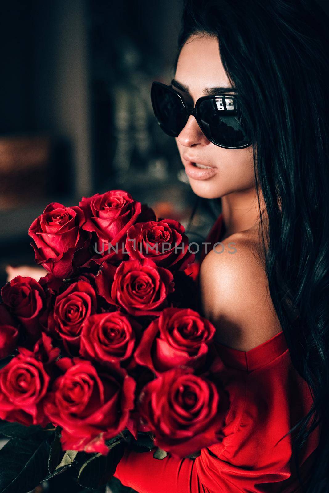 Charming young woman in red sexy dress and sunglasses posing with a bouquet of red roses. photo of a seductive woman with black hair. Selective focus, filmgrain by Ashtray25