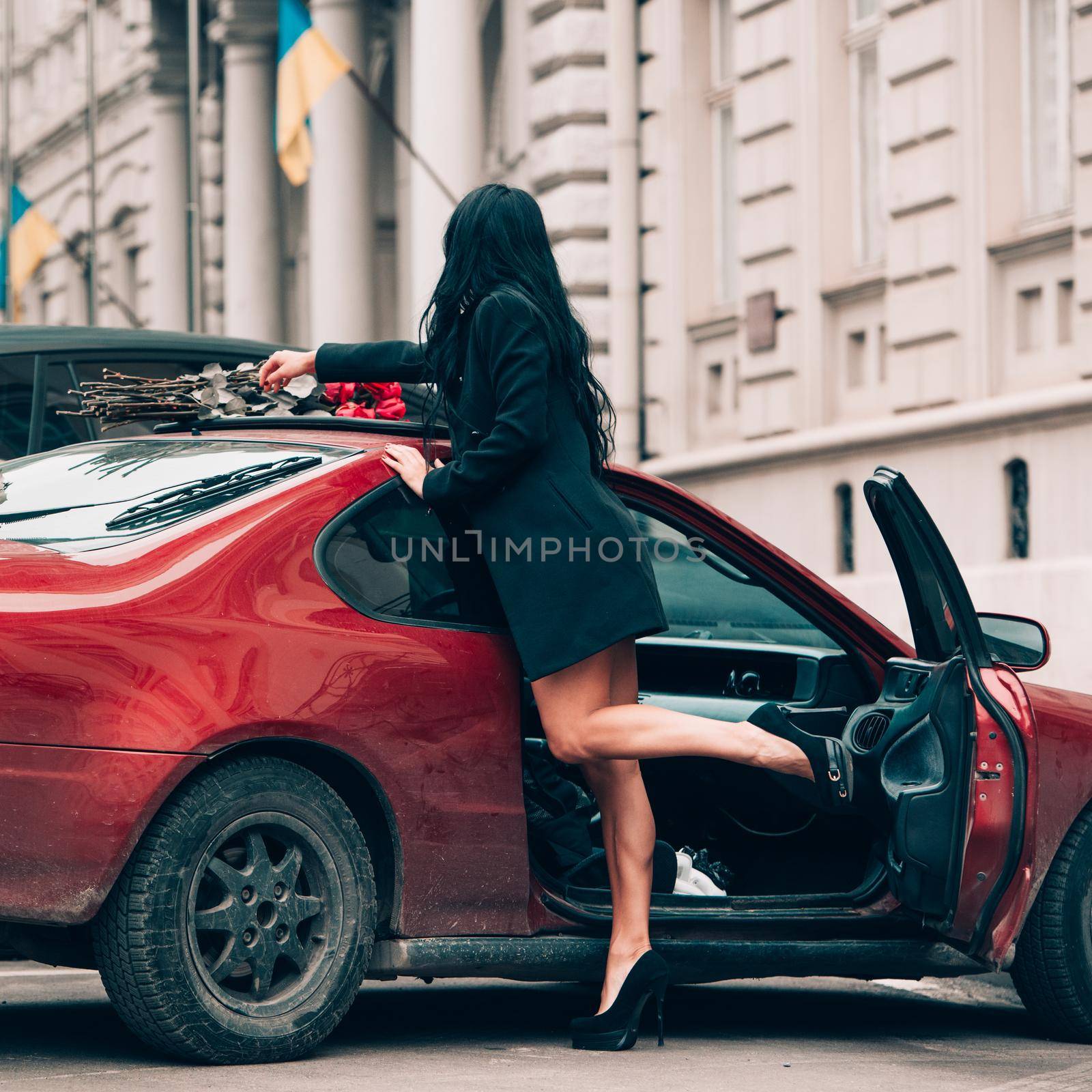 Charming young woman in red sexy dress posing. Sensual gorgeous young woman on high heels in red outfit. Photo of attractive long legs