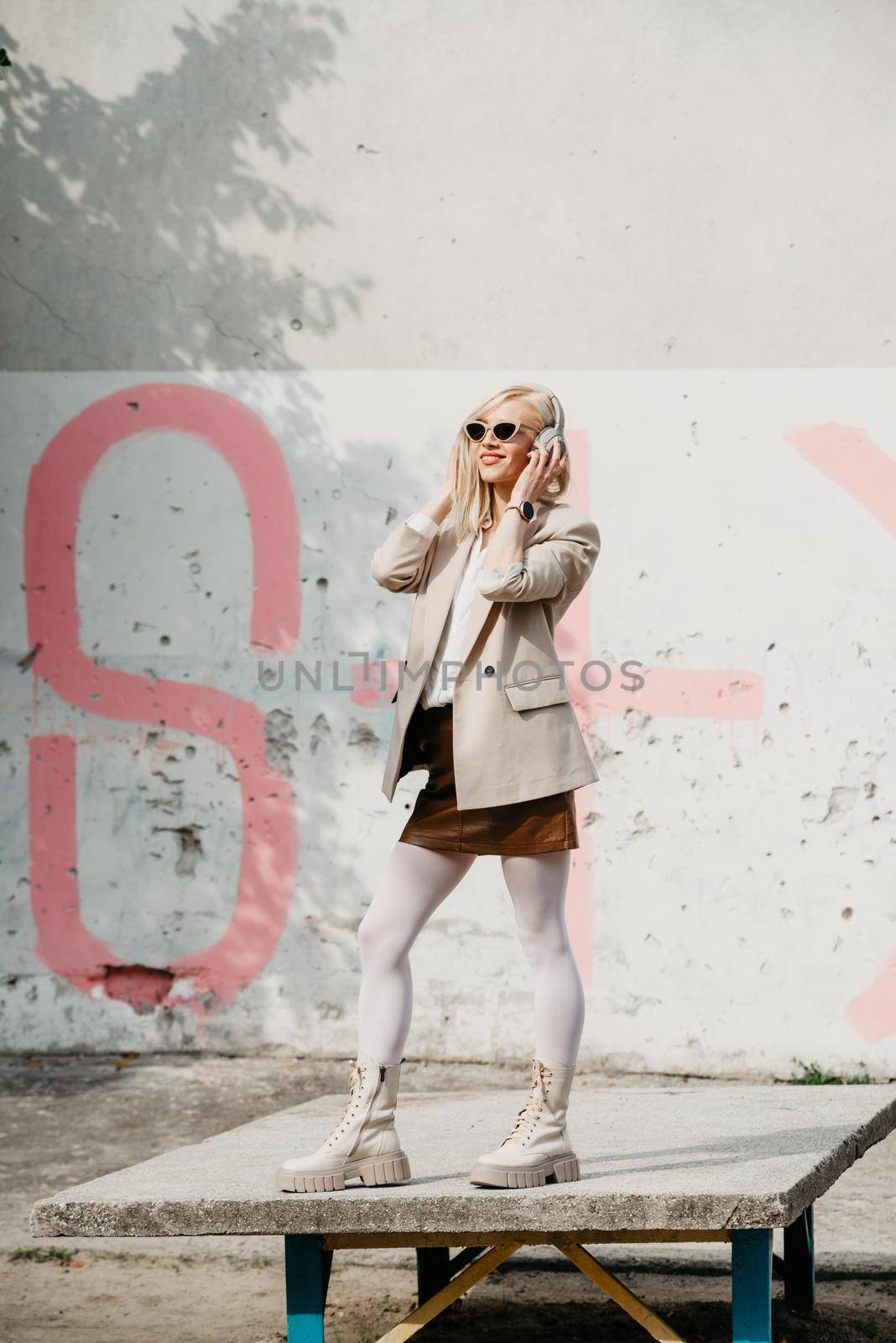 Portrait of blonde woman in headphones and sunglasses . Hipster fashion model wear stylish wireless headphones enjoy listen new cool music. by Ashtray25