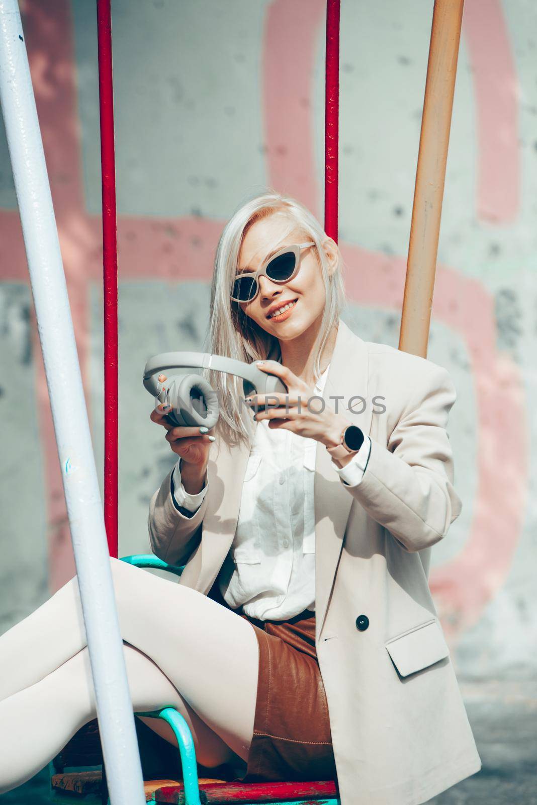 Portrait of blonde woman with headphones in hands. Hipster fashion model wear stylish wireless headphones enjoy listen new cool music. by Ashtray25