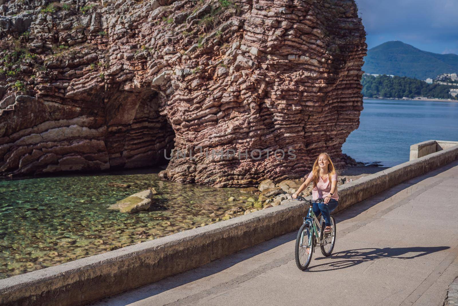 Woman tourist on a bicycle explores Budva in Montenegro. Cycling in Montenegro concept.