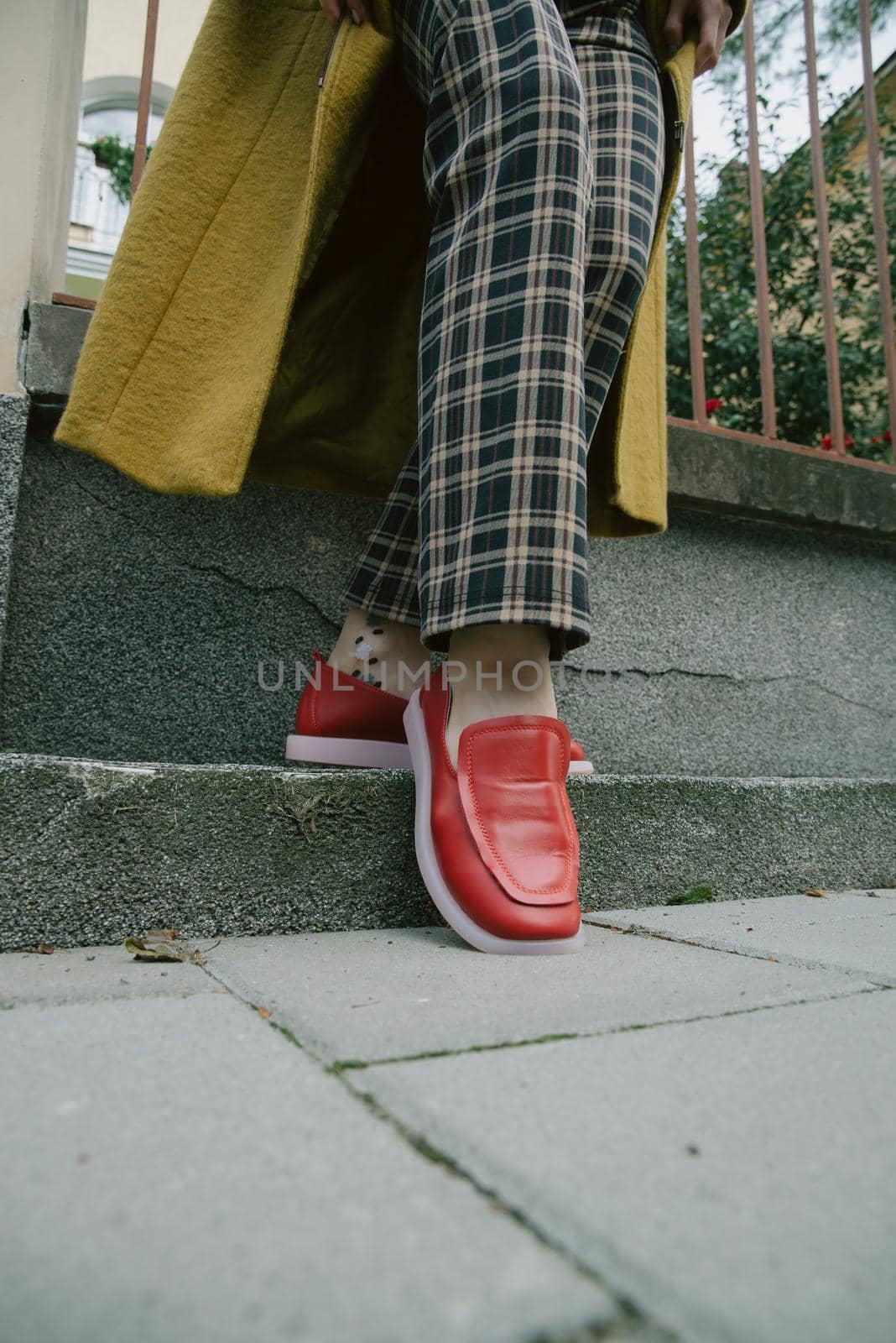 woman's legs in chequered trousers and red shoes.