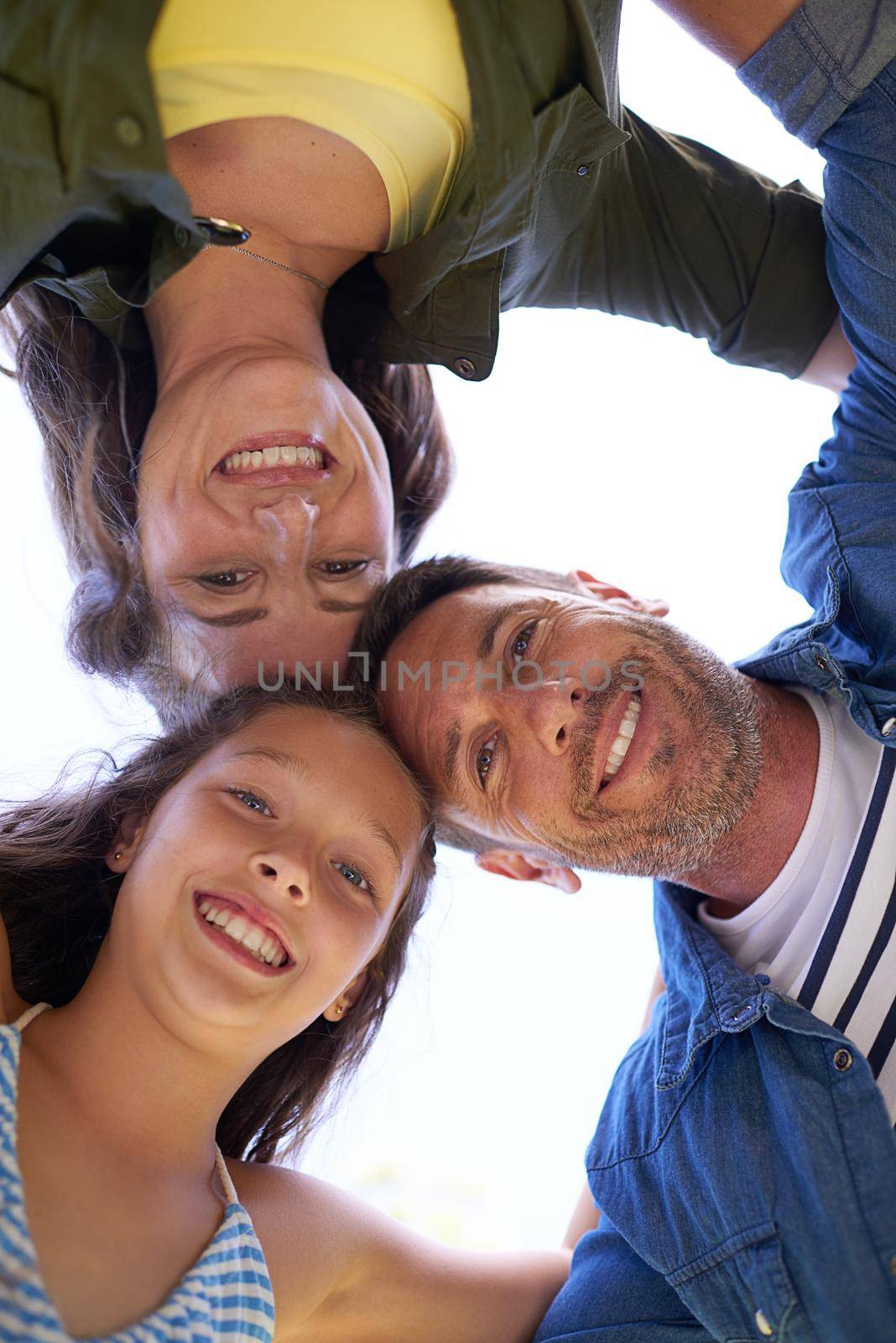 Low angle shot of a young family standing in a huddle outside.