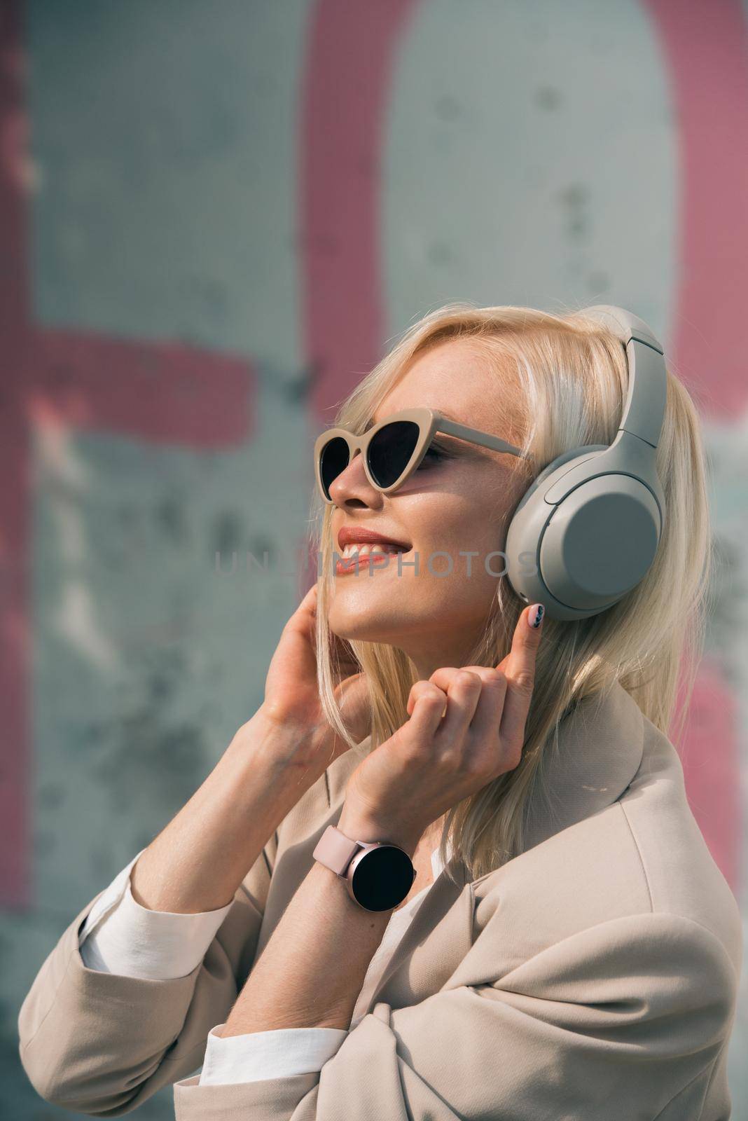 Portrait of blonde woman in headphones listening music with sunglasses. model wear stylish wireless headphones enjoy listen new cool music. by Ashtray25