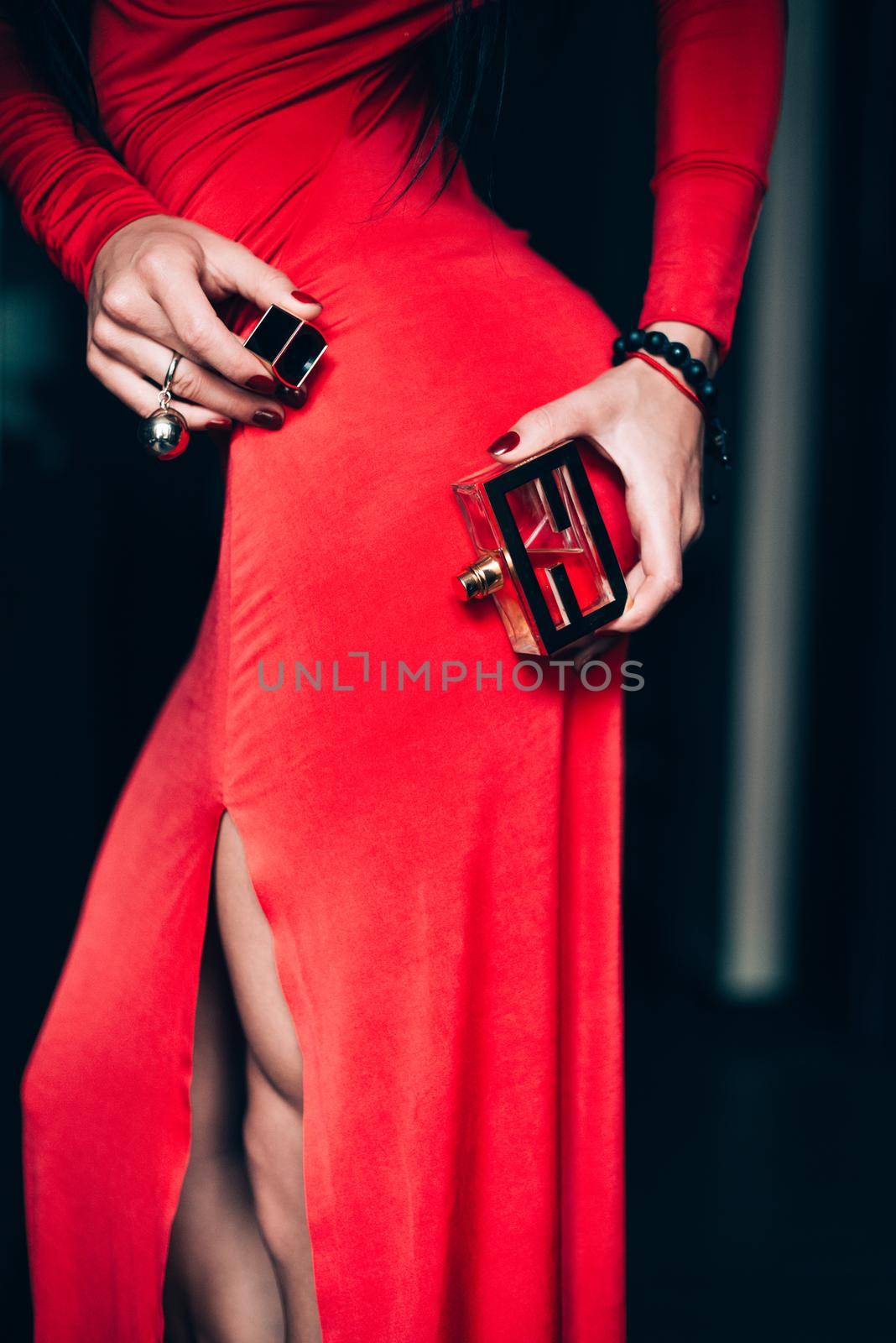 Charming young woman in red sexy dress posing. Sensual gorgeous young woman hold parfume in hands. obsession with red. Selective focus, filmgrain