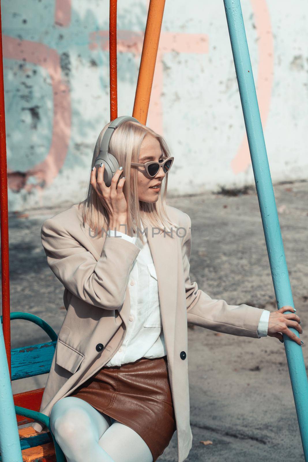 Portrait of blonde woman in headphones listening music with sunglasses. Hipster fashion model wear stylish wireless headphones enjoy listen new cool music. by Ashtray25