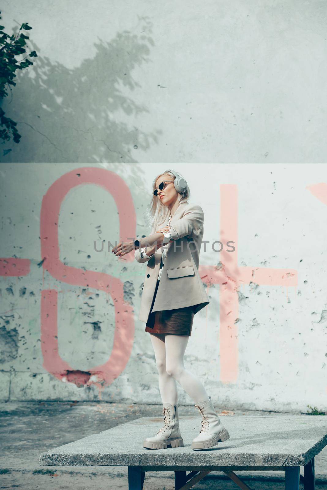 Portrait of blonde woman in headphones and sunglasses . Hipster fashion model wear stylish wireless headphones enjoy listen new cool music. by Ashtray25