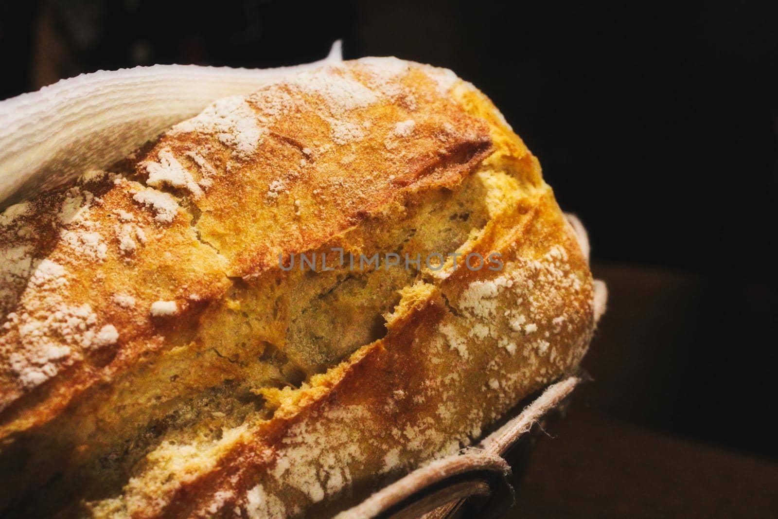 Freshly baked rustic white wheat flour bread loaf roll in a basket against a black background by tennesseewitney