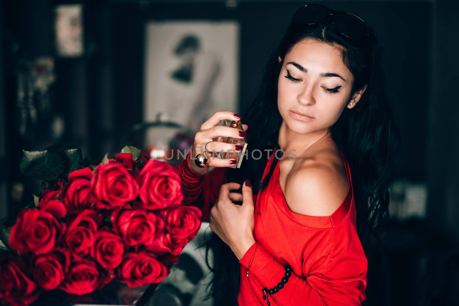 Charming young woman in red sexy dress posing. Sensual gorgeous young woman hold parfume in hands. obsession with red. Selective focus, filmgrain