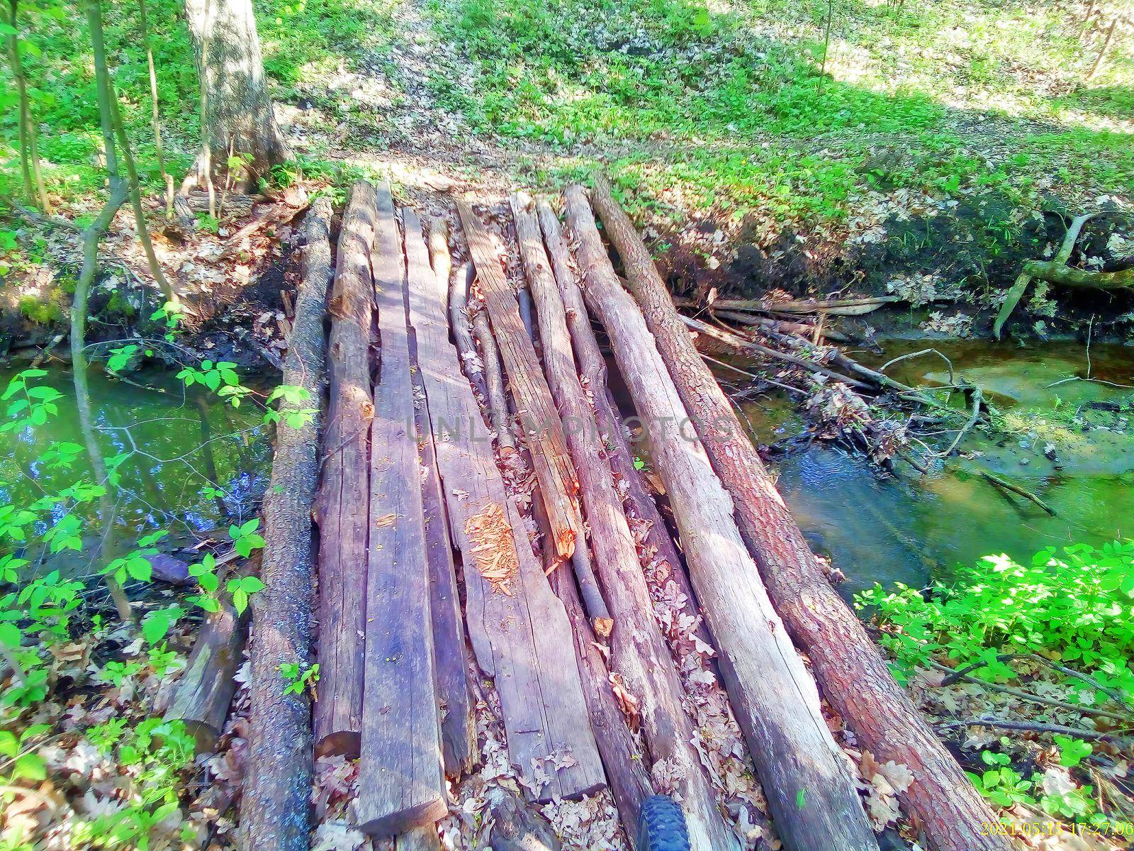 An old log bridge without a parapet over a small stream in the woods on image