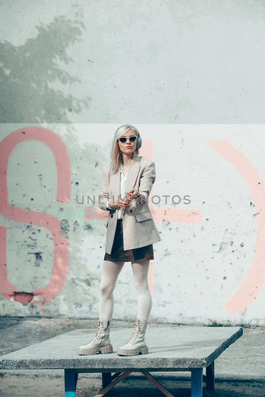 Portrait of blonde woman in headphones and sunglasses . Hipster fashion model wear stylish wireless headphones enjoy listen new cool music. by Ashtray25