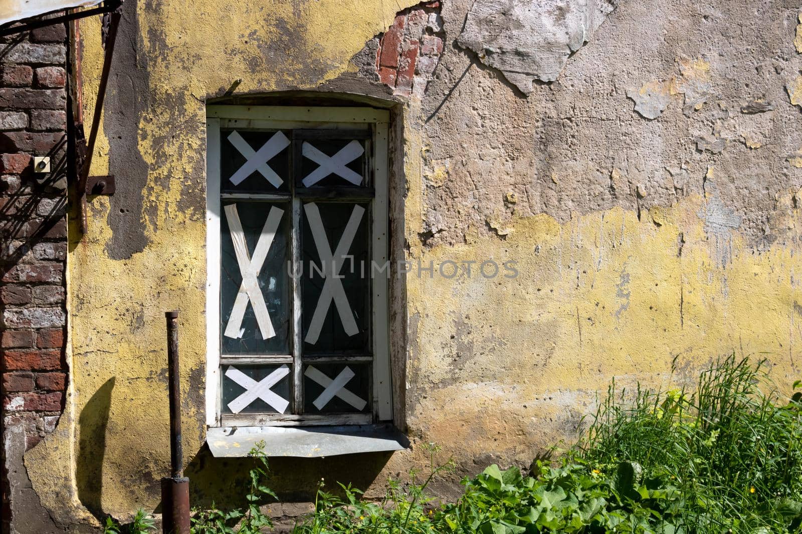 A shabby, rough, cracked wall, taped windows. The concept of the devastation of war, poverty. by lapushka62