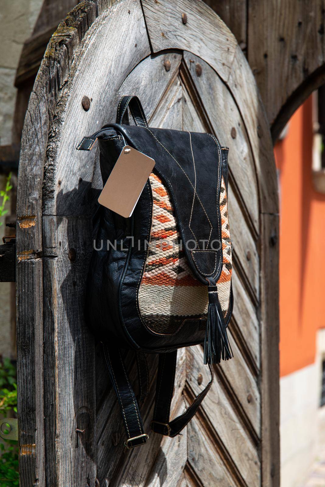 Black leather backpack with a pattern on the wooden door. Street photo