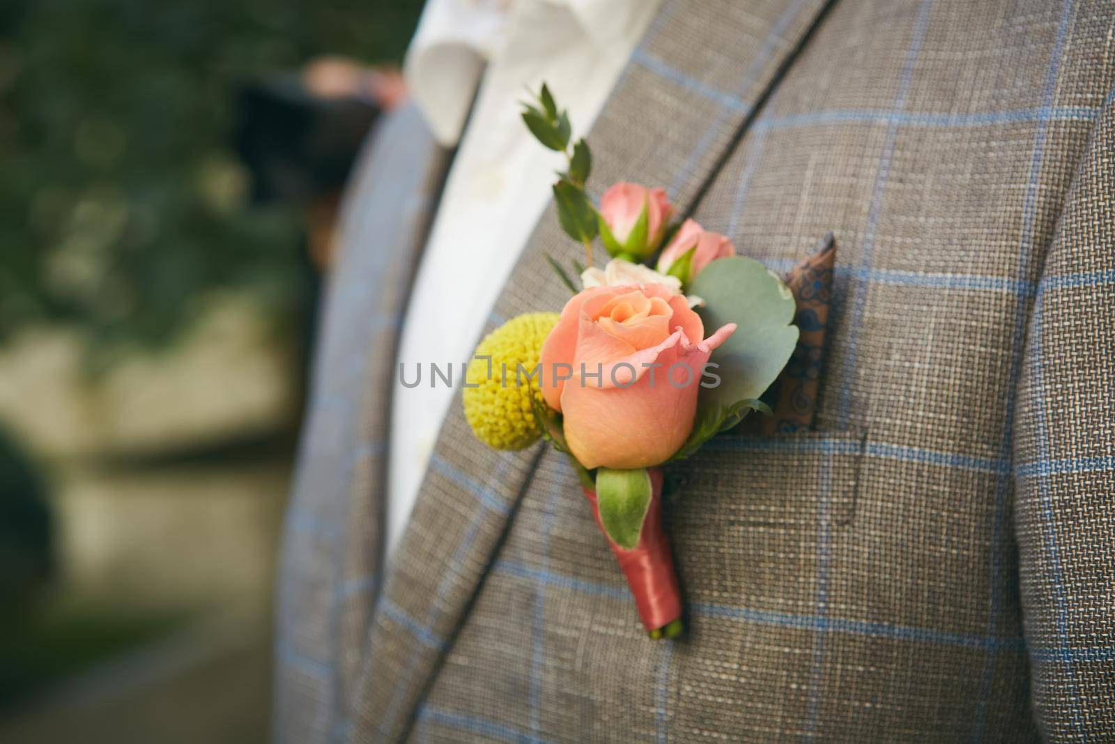 Close up image of beautiful boutonniere on the groom's jacket. Soft focus on boutonniere.