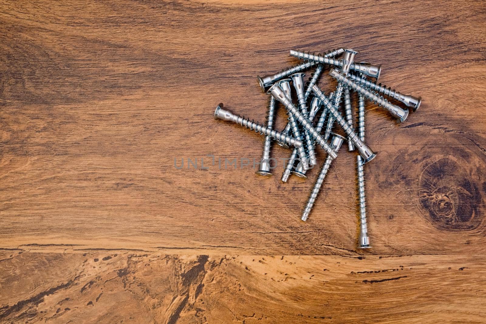 Close up of hex bolts screw for furniture assembly on wooden background. Top view. by leonik