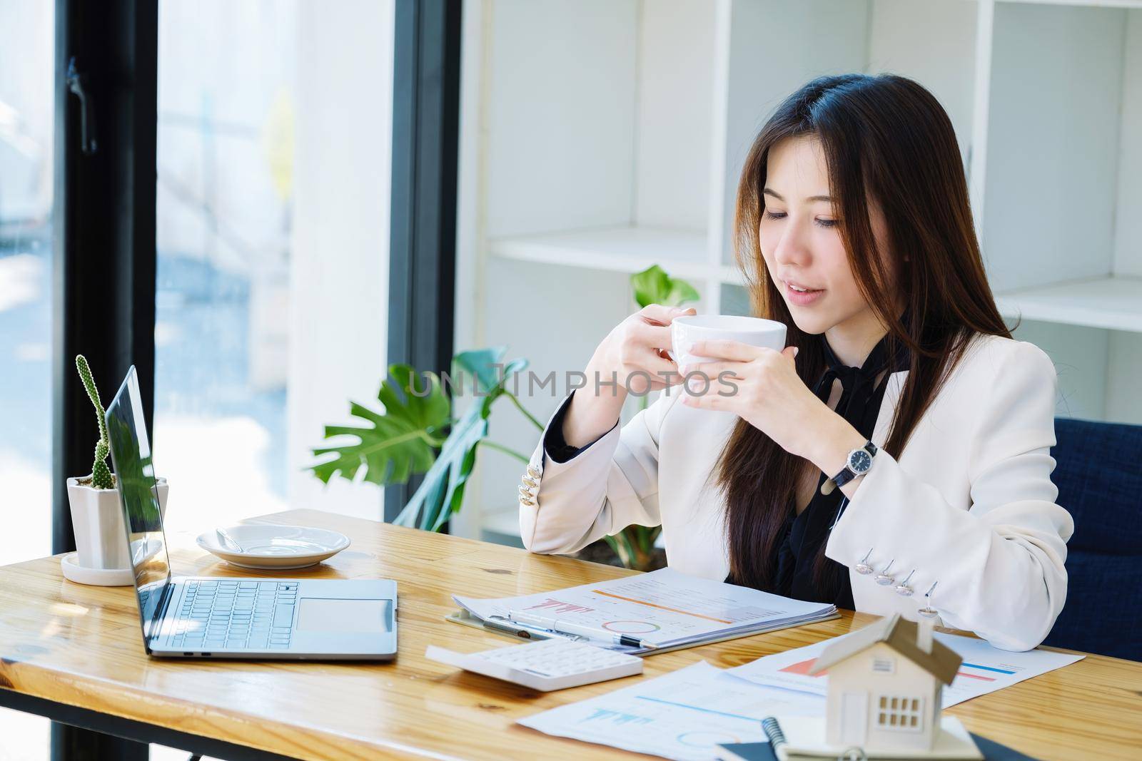 Accountant, businessman, Asian real estate agent taking a coffee break after successfully closing a house and land sale to a client