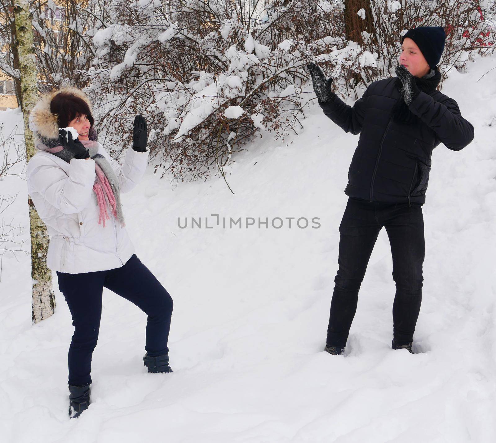 Elderly mother and son teenager on a background of snow with a snowball. by gelog67